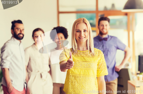 Image of woman showing thumbs up over creative office team