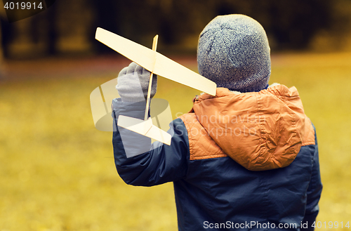 Image of happy little boy playing with toy plane outdoors