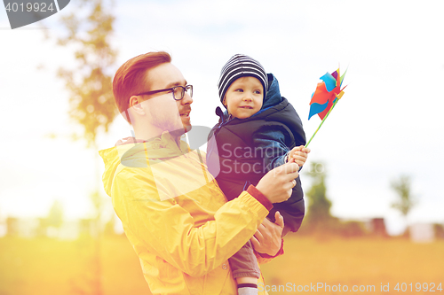 Image of happy father and son with pinwheel toy outdoors