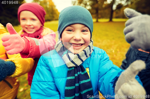 Image of happy children showing thumbs up in autumn park