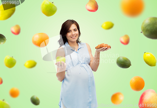 Image of happy pregnant woman with apple and croissant