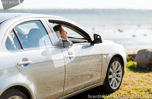 Image of happy teenage girl or young woman in car