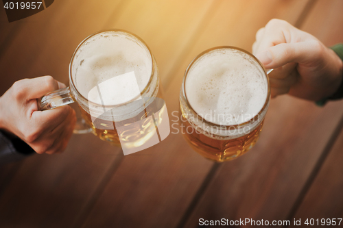 Image of close up of hands with beer mugs at bar or pub