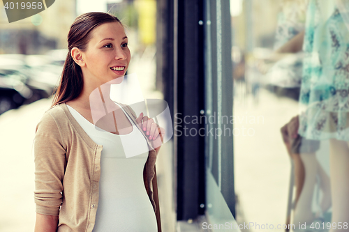 Image of happy pregnant woman with shopping bags at city