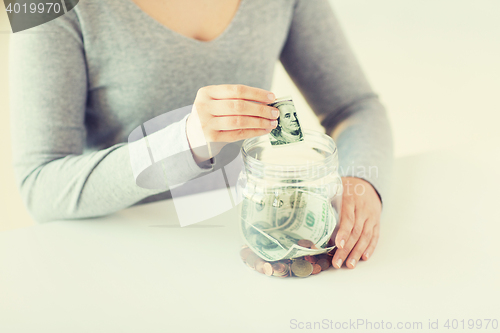 Image of close up of woman hands and dollar money in jar