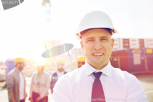 Image of group of smiling builders in hardhats outdoors