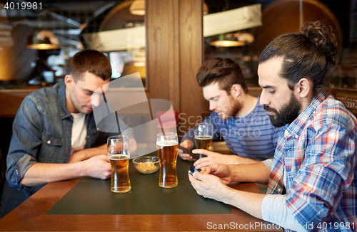 Image of men with smartphones drinking beer at bar or pub