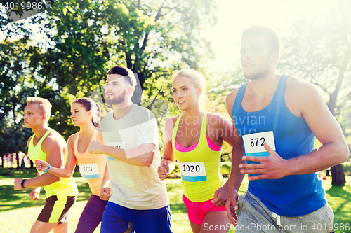 Image of happy young sportsmen racing wit badge numbers