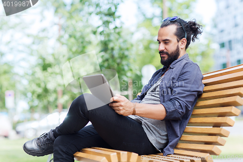 Image of man with tablet pc sitting on city street bench