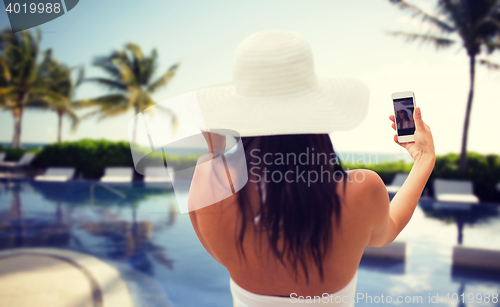 Image of woman taking selfie with smartphone on beach