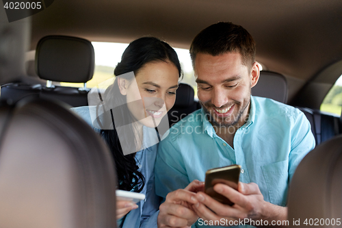 Image of man and woman with smartphones driving in car