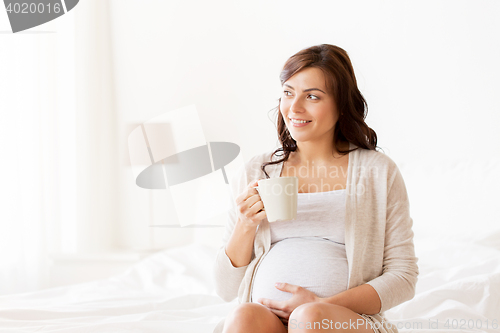 Image of happy pregnant woman with cup drinking tea at home