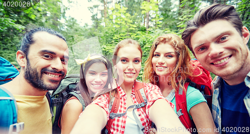 Image of friends with backpack taking selfie in wood