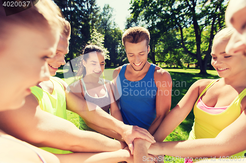 Image of group of happy friends with hands on top outdoors