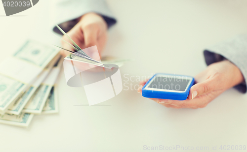 Image of close up of woman hands with smartphone and money