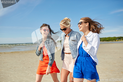Image of group of smiling women in sunglasses on beach