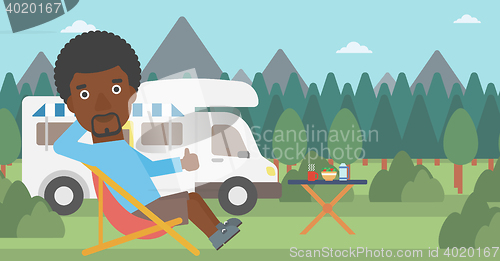 Image of Man sitting in chair in front of camper van.