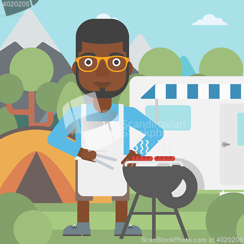 Image of Man having barbecue in front of camper van.