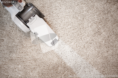 Image of Top view of cordless handheld vacuum cleaner on beige carpet