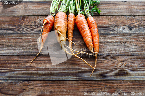 Image of Raw carrot with green leaves on wooden background