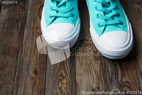 Image of Blue sneakers on empty Brown parquet