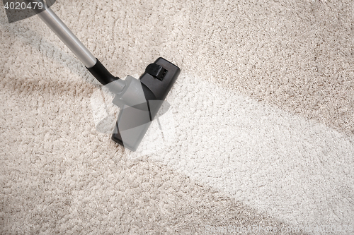 Image of Vacuum cleaner vacuuming dusty carpet