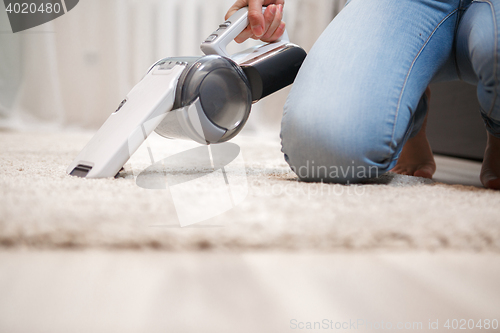 Image of Housewife cleaning fluffy carpet in living room
