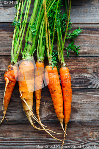 Image of Raw carrot with green leaves on wooden background