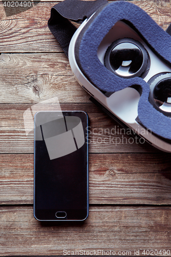 Image of Modern smartphone with empty screen and virtual reality goggles