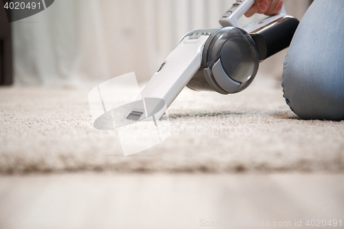 Image of Process of cleaning carpet with help portable vacuum cleaner