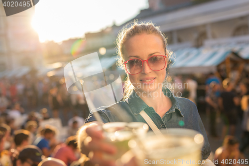 Image of Beautiful young girl toasting on outdoor urban event.