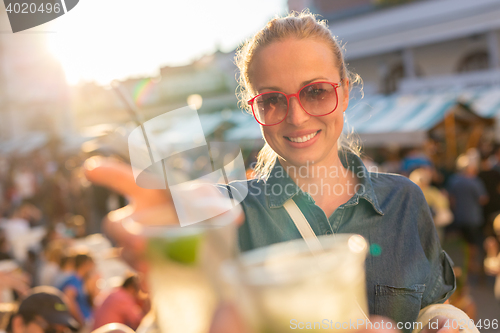 Image of Beautiful young girl toasting on outdoor urban event.