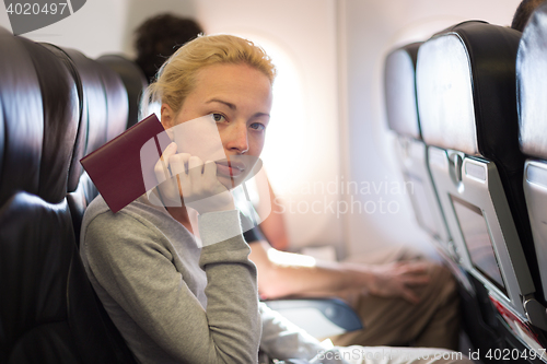 Image of Woman traveling by plae holding passport in her hand.