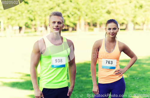 Image of happy friends or couple with racing badge numbers