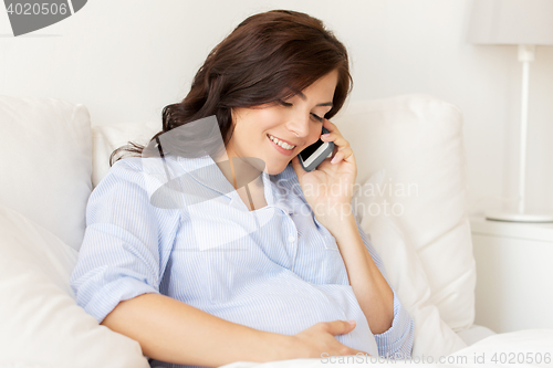 Image of happy pregnant woman calling on smartphone at home