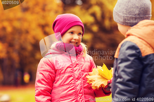 Image of little boy giving autumn maple leaves to girl