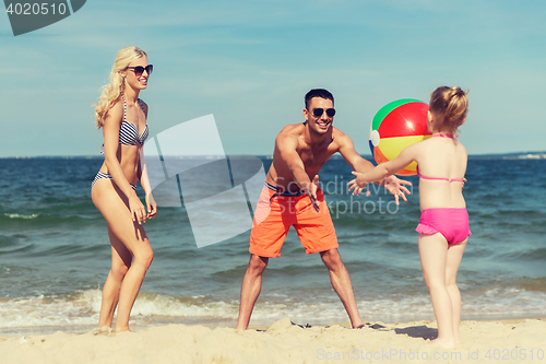 Image of happy family playing with inflatable ball on beach