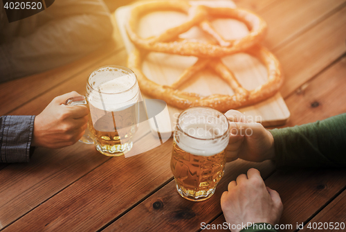 Image of close up of hands with beer mugs at bar or pub