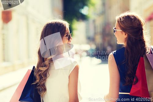 Image of happy women with shopping bags walking in city