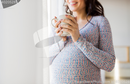 Image of close up of pregnant woman with tea cup at window