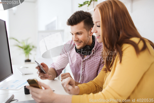 Image of happy creative team with smartphones at office
