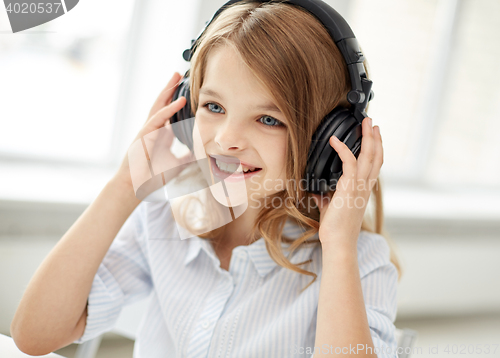 Image of smiling little girl with headphones at home