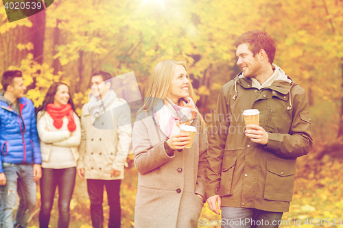 Image of group of smiling friend with coffee cups in park