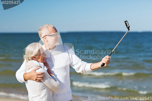 Image of happy senior couple hugging on summer beach