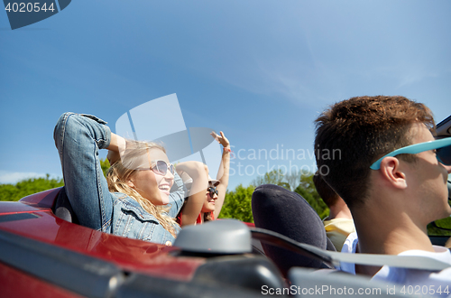 Image of happy friends driving in cabriolet car at country