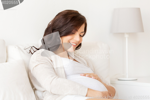 Image of happy pregnant woman lying on bed at home