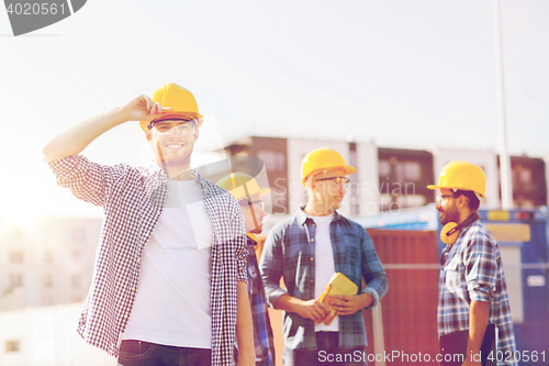 Image of group of smiling builders in hardhats outdoors