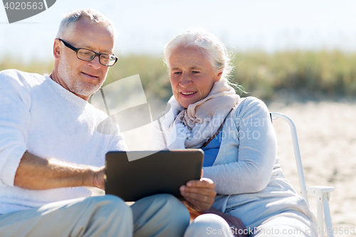 Image of happy senior couple with tablet pc on summer beach