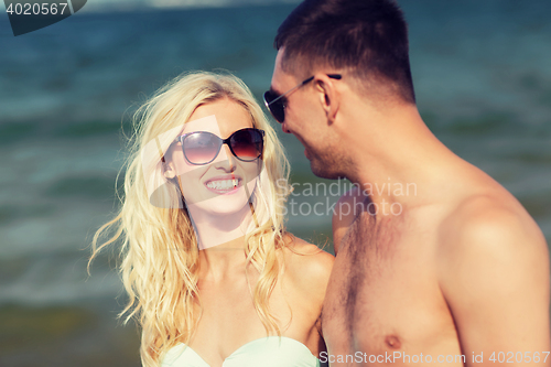 Image of happy couple in swimwear walking on summer beach