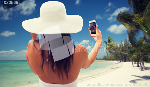 Image of woman taking selfie with smartphone on beach